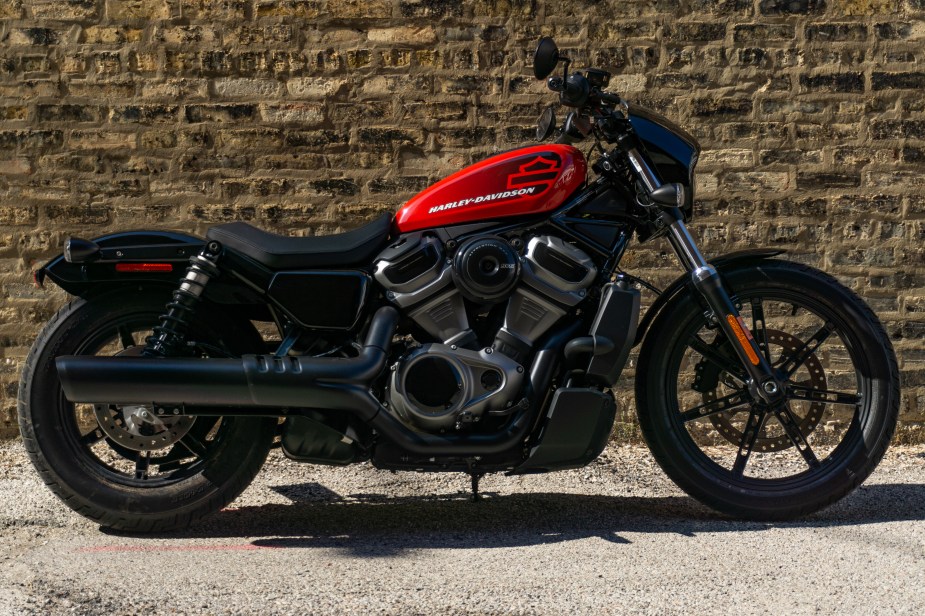 The right-side view of a red-and-black 2022 Harley-Davidson Nightster in front of a brown brick wall
