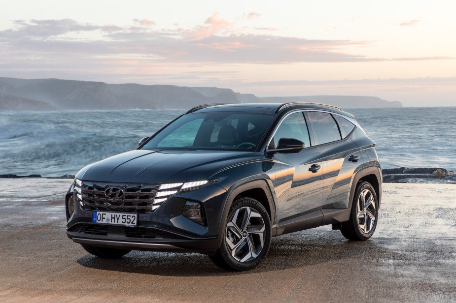 A dark-colored 2022 Hyundai Tucson, a compact SUV, parked in front of an oceanscape. 
