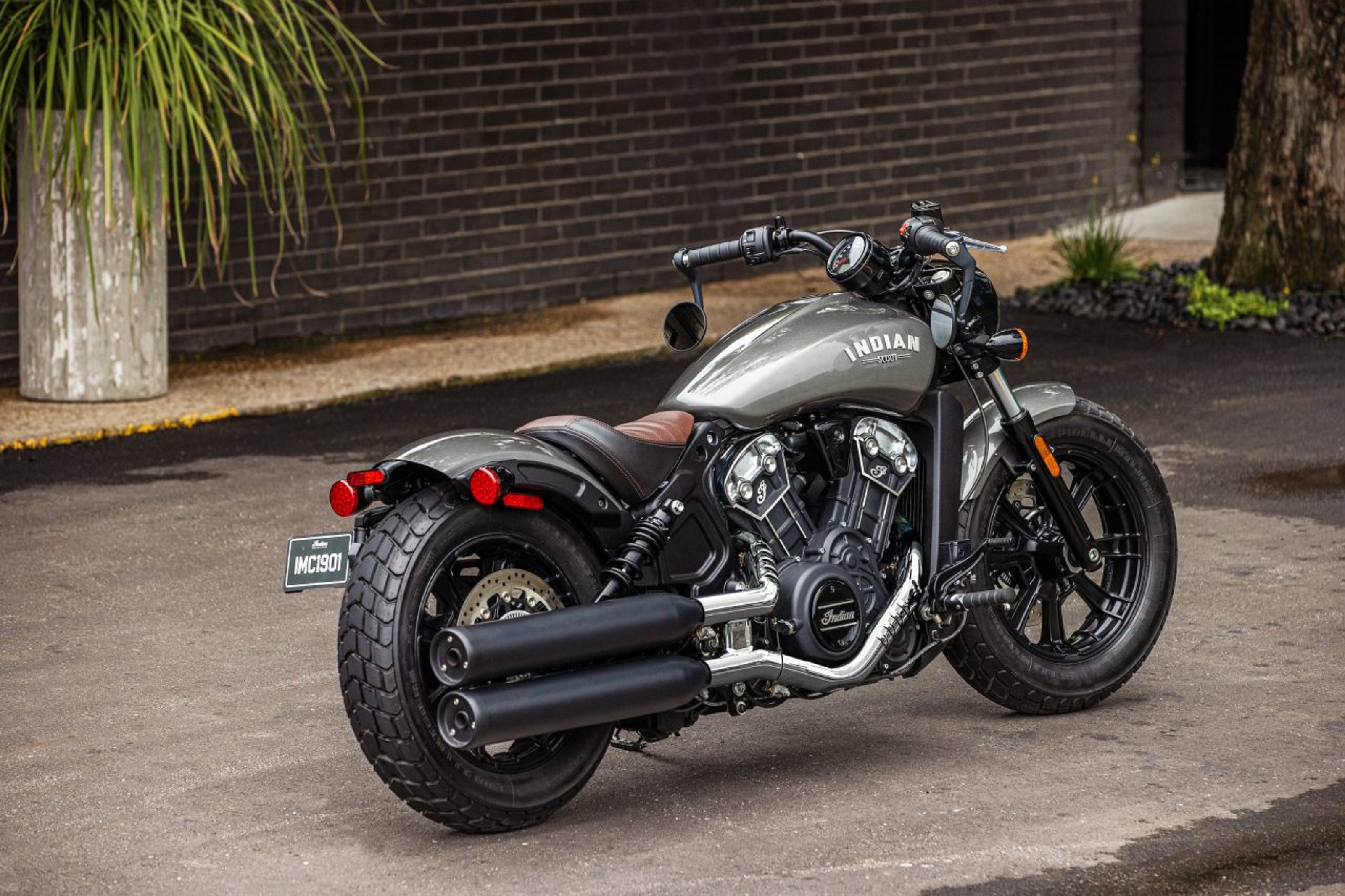 The rear 3/4 view of a gray 2022 Indian Scout Bobber next to a city shop