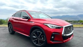 The 2022 Infiniti QX55 in red sitting in the corner of a parking lot.
