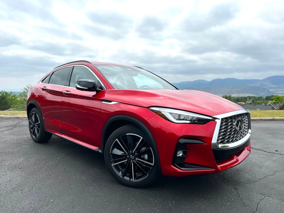 The 2022 Infiniti QX55 in red sitting in the corner of a parking lot.