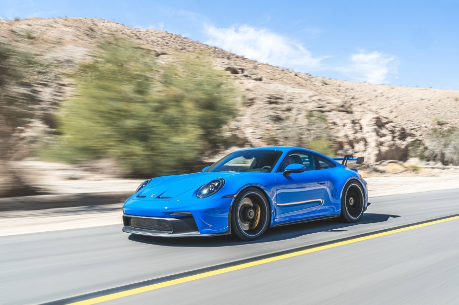 A blue 2022 Porsche 911 GT3 driving down a desert canyon road. Costs more than a 2023 Corvette Z06 with comparable performance figures
