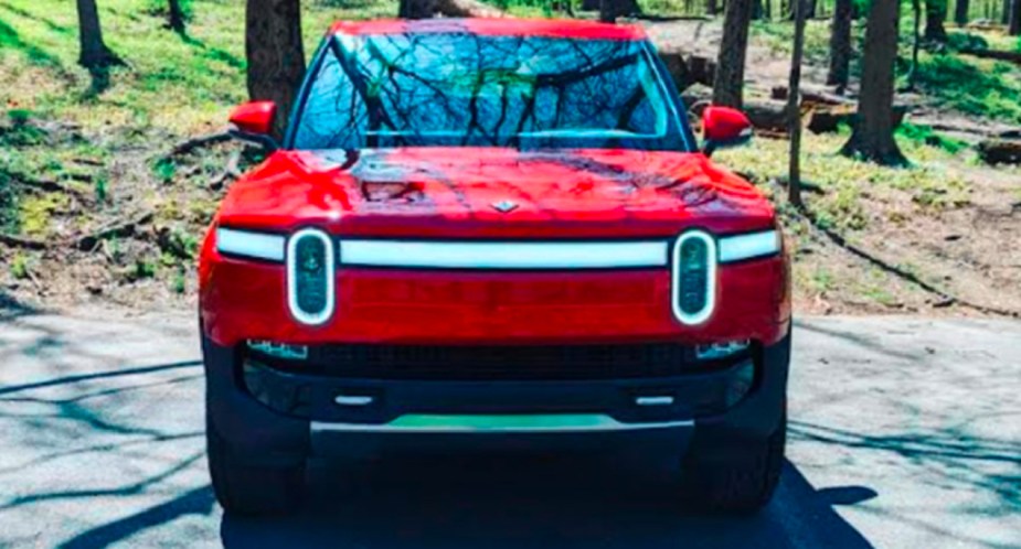 A red 2022 Rivian R1T Launch Edition electric pickup truck is parked. 