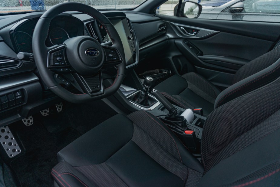 The black-with-red-stitching front seats and black dashboard of a 2022 Subaru WRX Premium