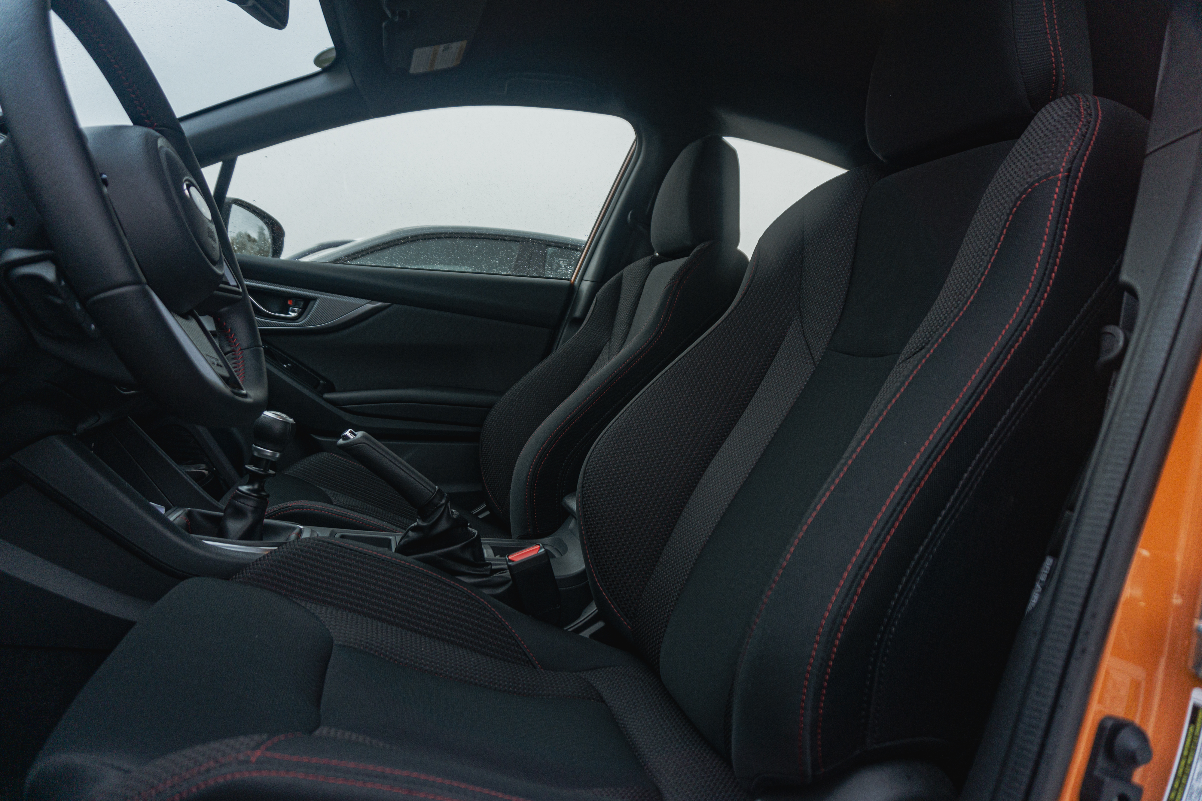 The black-with-red-stitching front seats in an orange 2022 Subaru WRX Premium