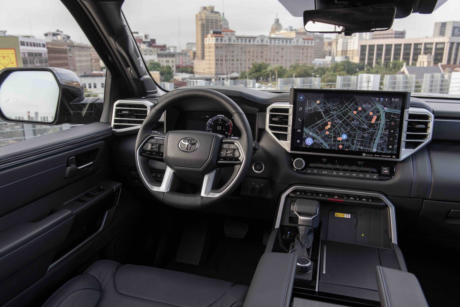 The premium interior of a Toyota Tundra pickup truck, a city visible outside its windshield.