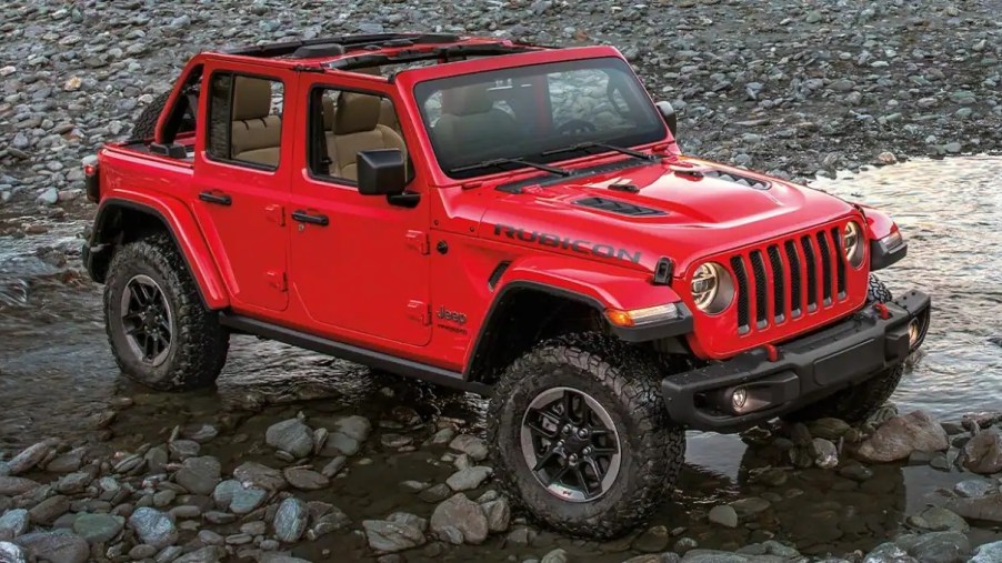 A red 2022 Jeep Wrangler sitting on rocks near water.