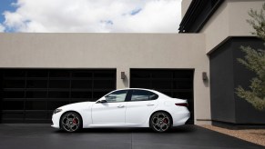 A white 2023 Alfa Romeo Giulia parks next to a modern home.