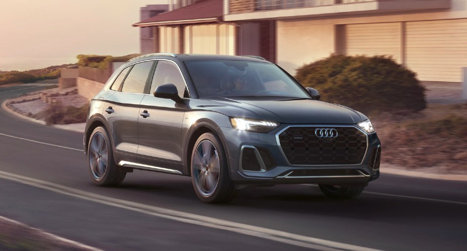 A blue 2023 Audi Q5 luxury compact SUV is driving on the road. 