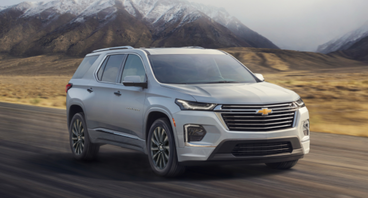 A gray 2023 Chevrolet Traverse midsize SUV is driving on the road.