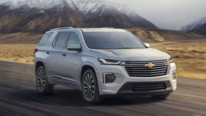 A gray 2023 Chevrolet Traverse midsize SUV is driving on the road.