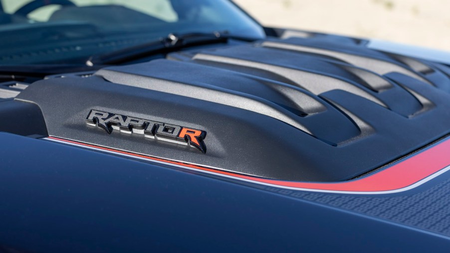 Closeup of the badges on the hood scoop of an F-150 Raptor R above its V8 engine.