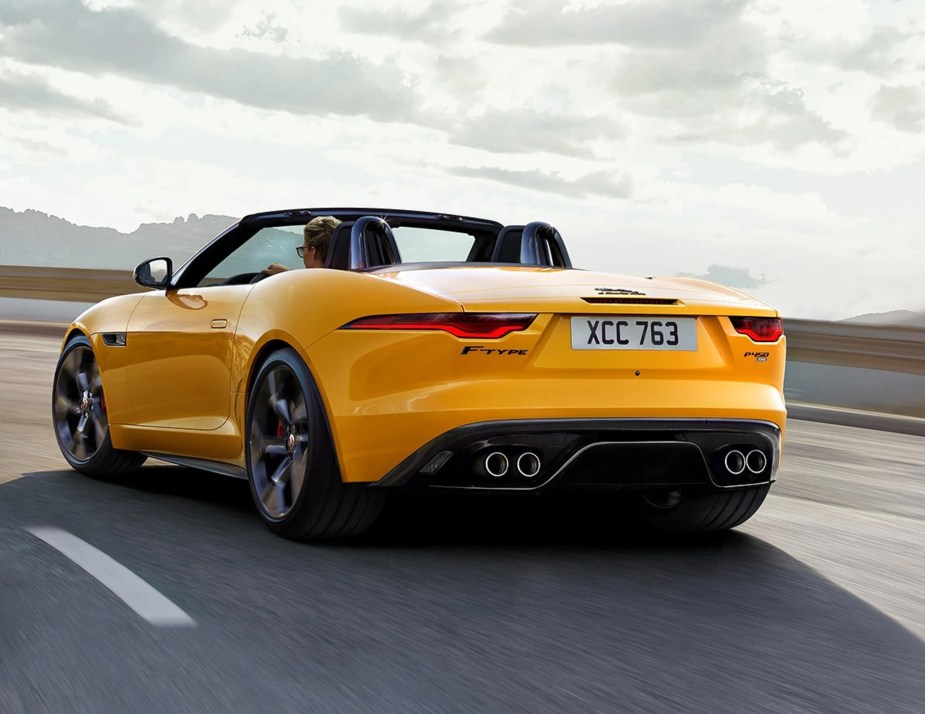 The rear 3/4 view of a yellow 2023 Jaguar F-Type P450 AWD R-Dynamic Convertible on a mountside road