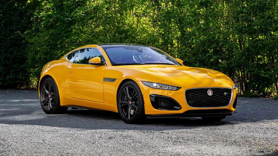 A yellow 2023 Jaguar F-Type R Coupe parked on a gravel tree-lined drive