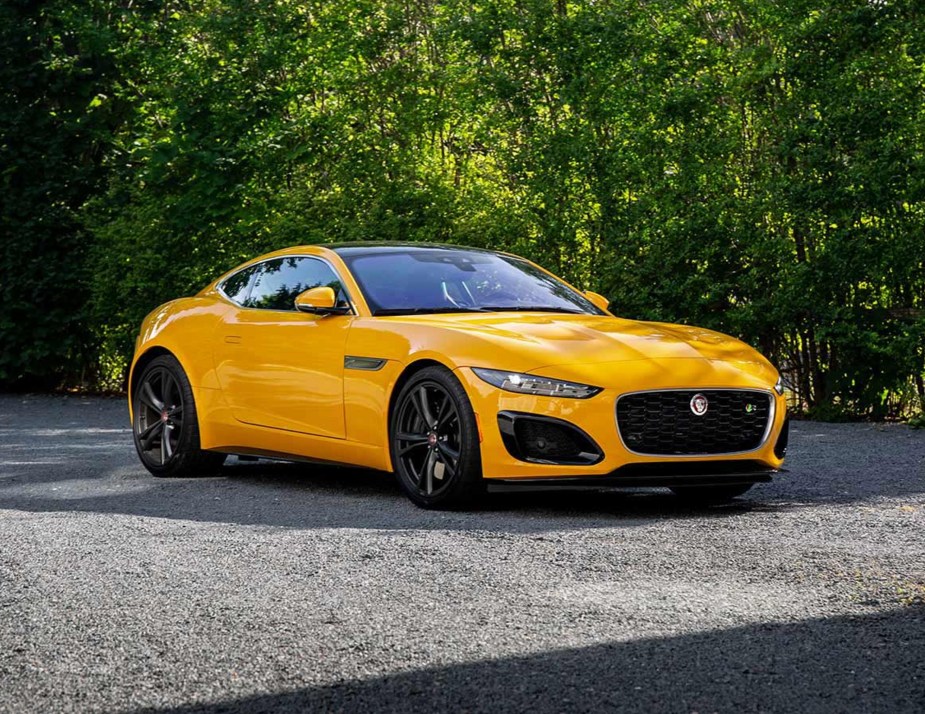A yellow 2023 Jaguar F-Type R Coupe parked on a gravel tree-lined drive