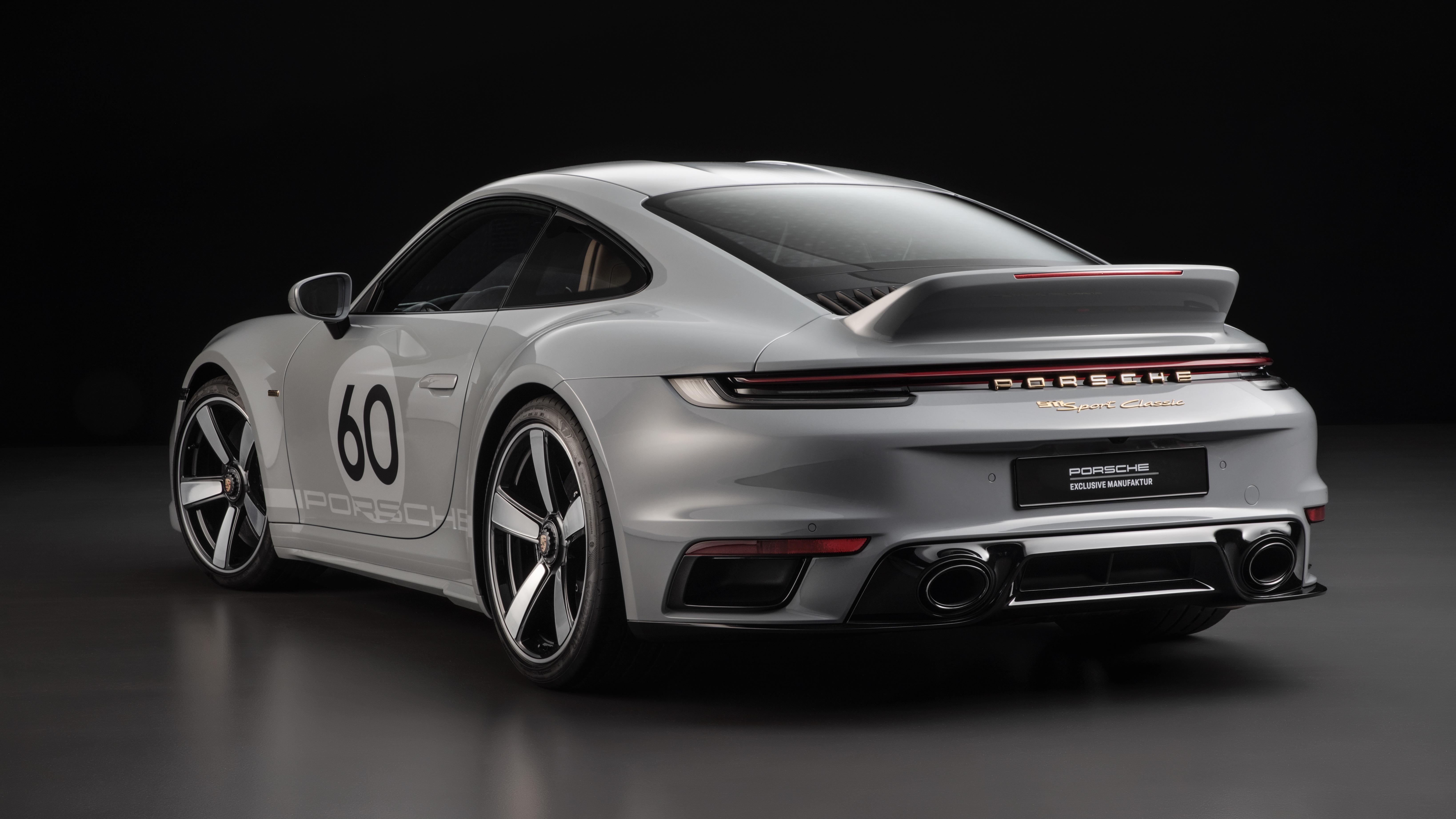 The rear 3/4 view of a gray-on-gray 2023 Porsche 911 Sport Classic in a black studio