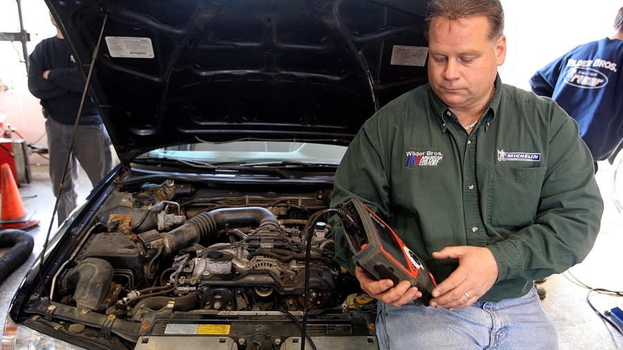 A mechanic reads a car's diagnostic trouble codes with a dedicated scanning tool
