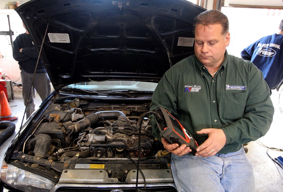 A mechanic reads a car's diagnostic trouble codes with a dedicated scanning tool