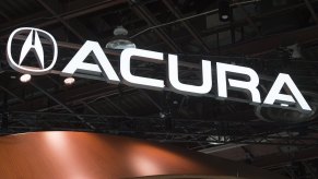 An Acura sign lit up in white on a black background.