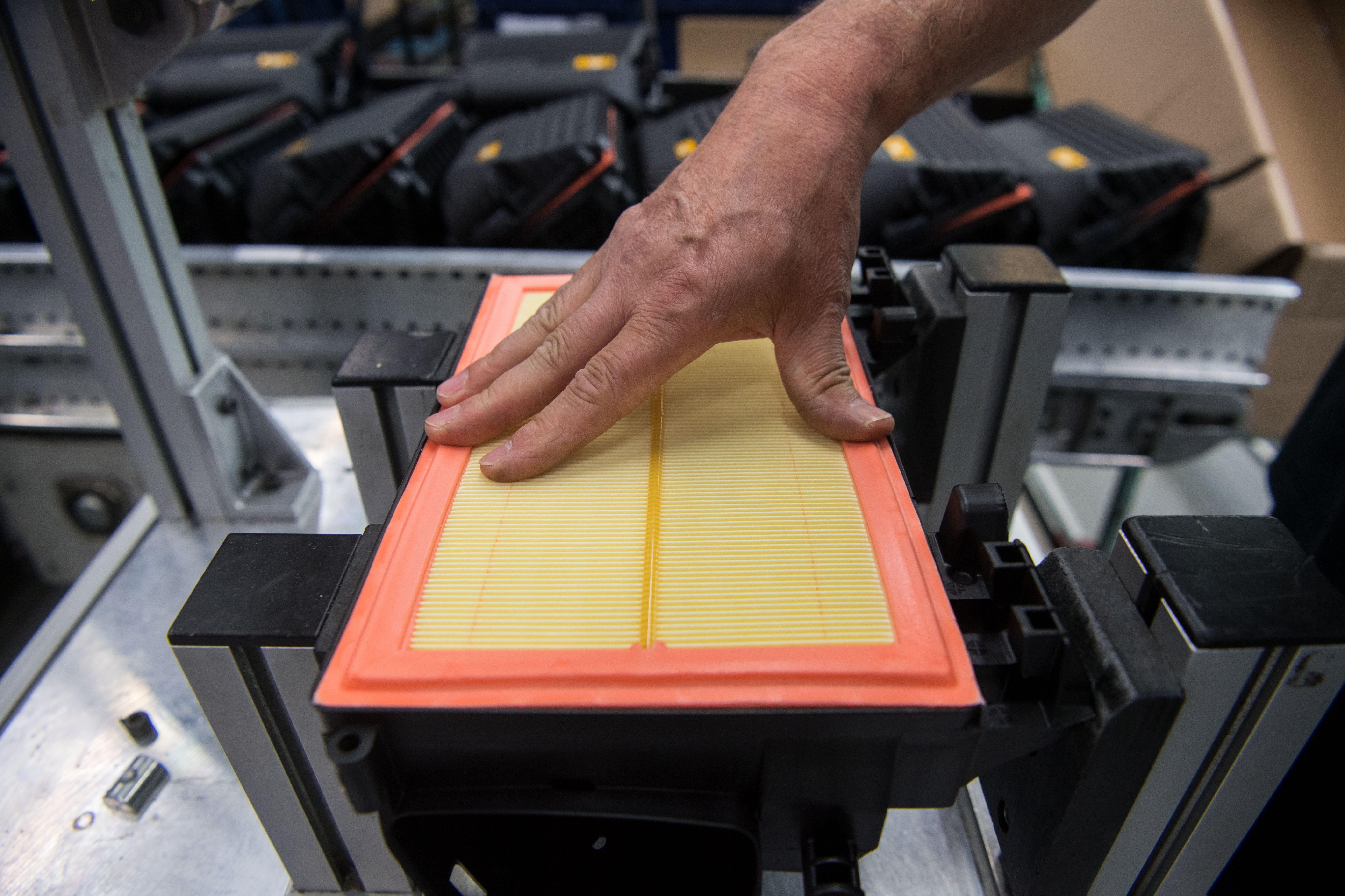 An orange-and-yellow engine air filter being assembled in Mann+Hummel's factory