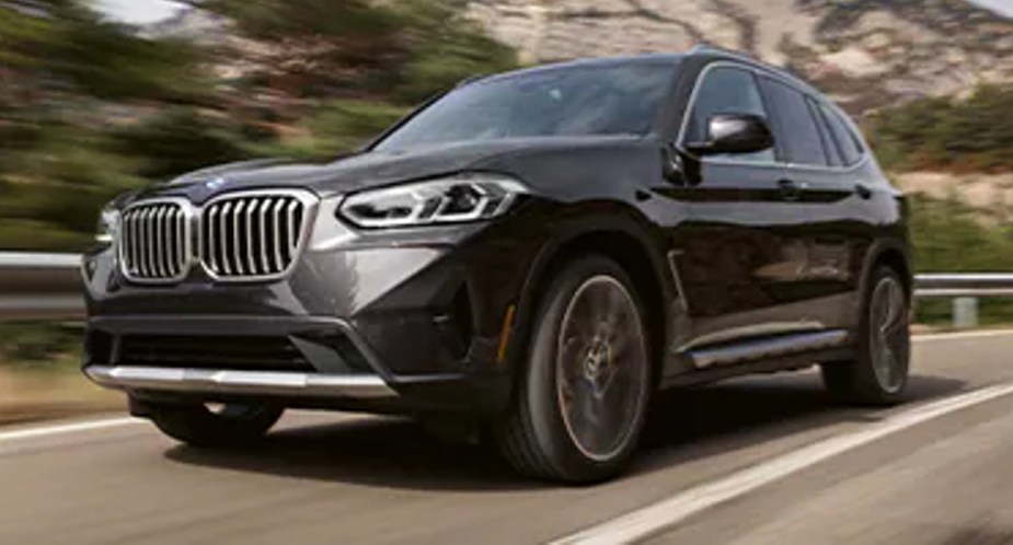 A gray BMW X3 luxury compact SUV is driving on the road. 