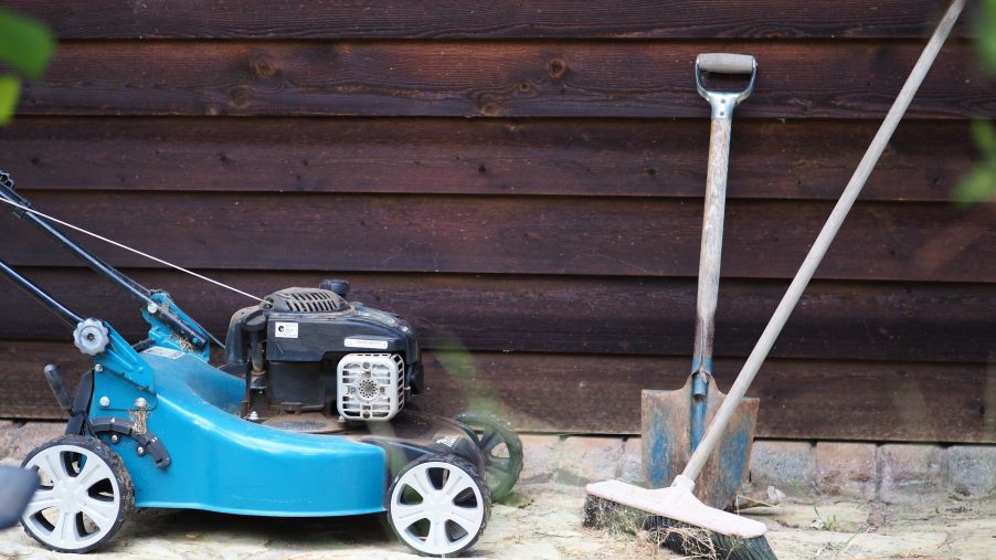 A blue lawn mower stopped against a wall
