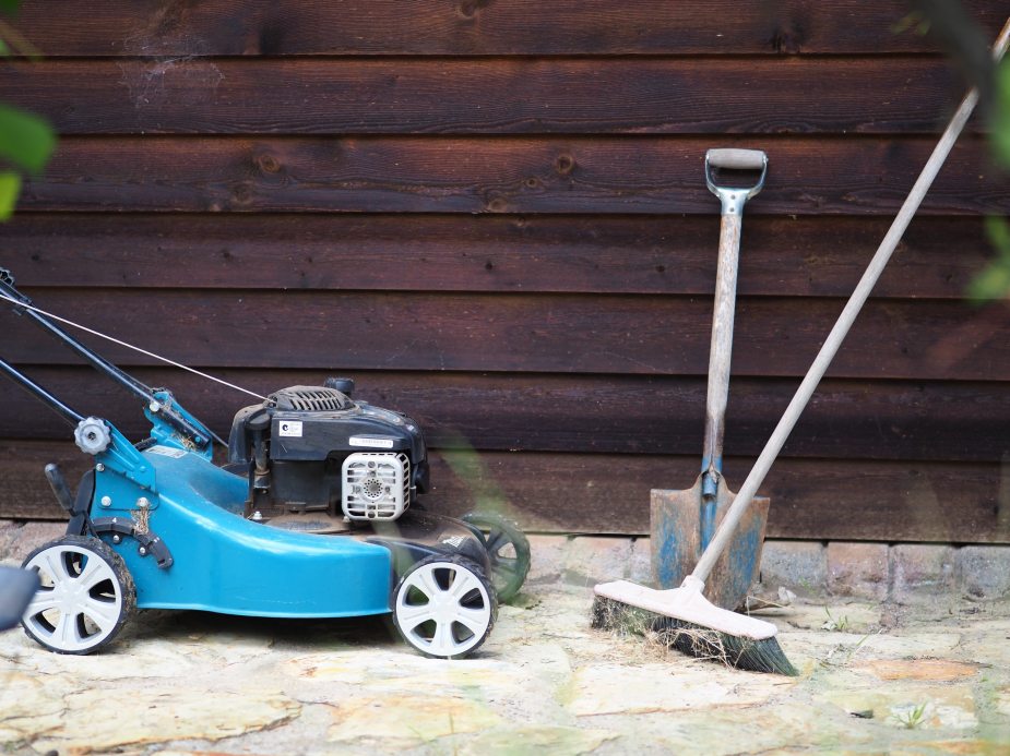 A blue lawn mower stopped against a wall