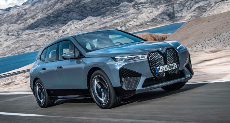 A blue 2022 BMW iX electric midsize SUV is driving on the road. 