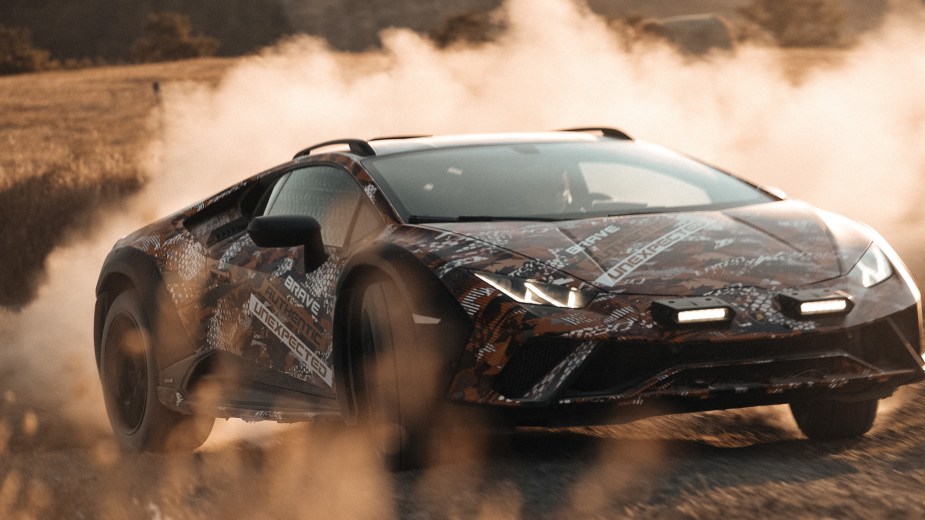 A black-orange-and-white camouflaged production Lamborghini Huracan Sterrato sliding through the dirt
