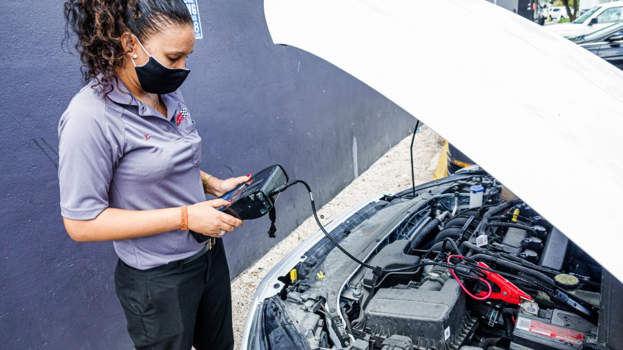 A woman testing a car battery in a parking lot