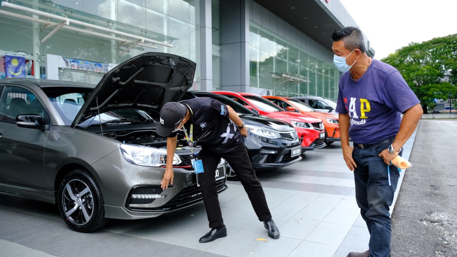 A person checking a car for potentially more quality issues at a dealership.