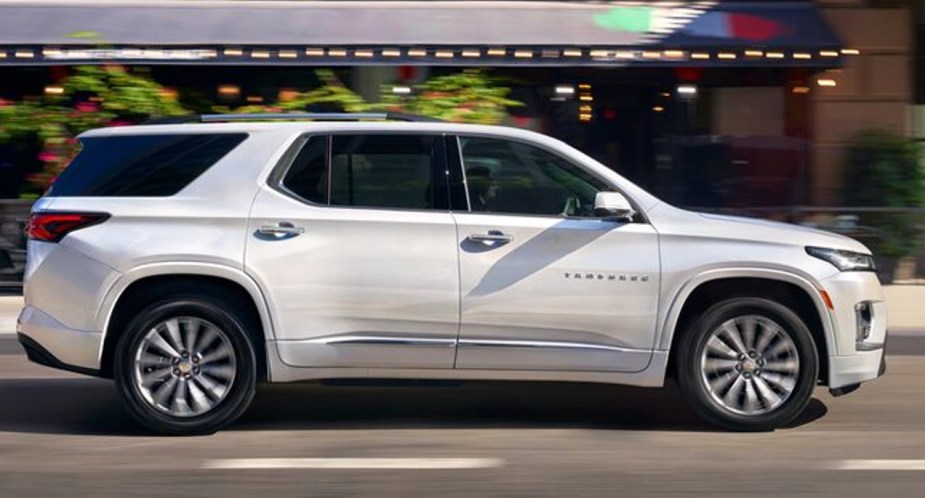 A white 2023 Chevrolet Traverse midsize SUV is driving on the road. 