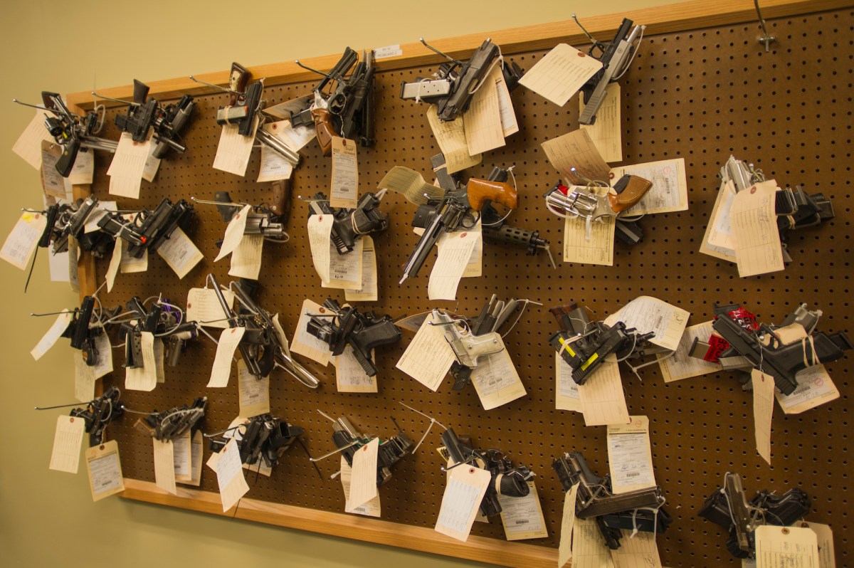 Confiscated guns, potentially stolen guns, hanging on a wall. 