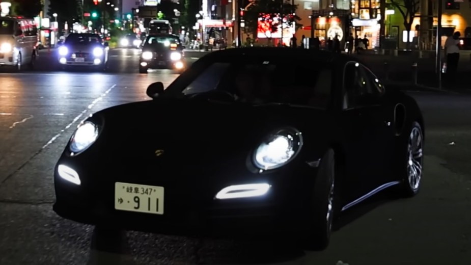 Custom Porsche 911 with Musou Black, the world's darkest paint color, driving on a street in Japan at night