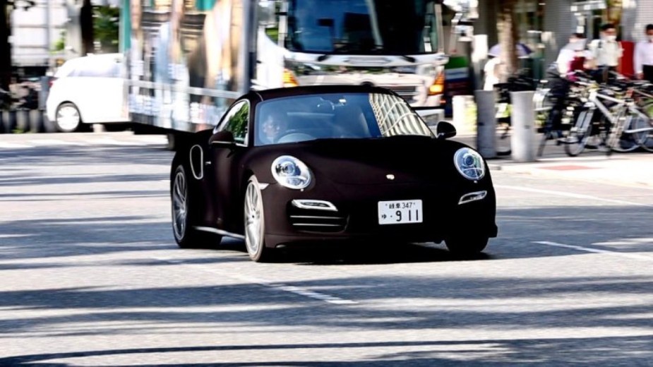 Custom Porsche 911 with Musou Black, the world's darkest paint color, driving on a street in Japan during the day