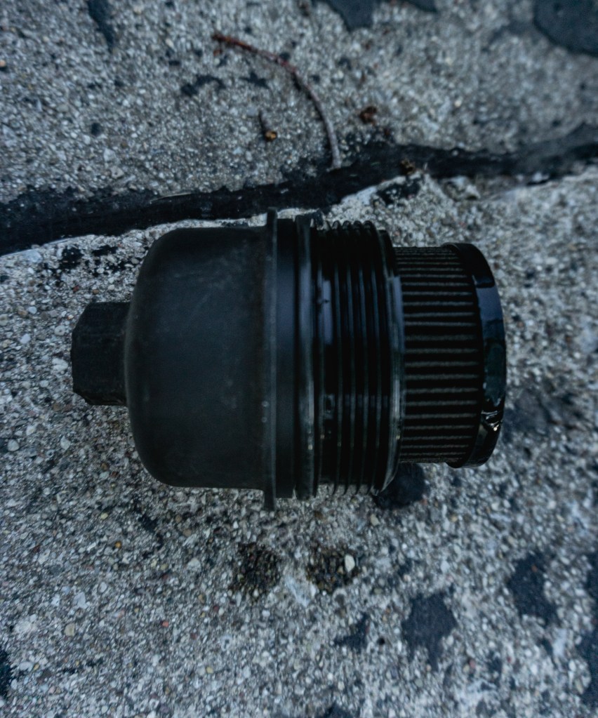The dirty cartridge oil filter and black housing cap from a 2013 Fiat 500 Abarth