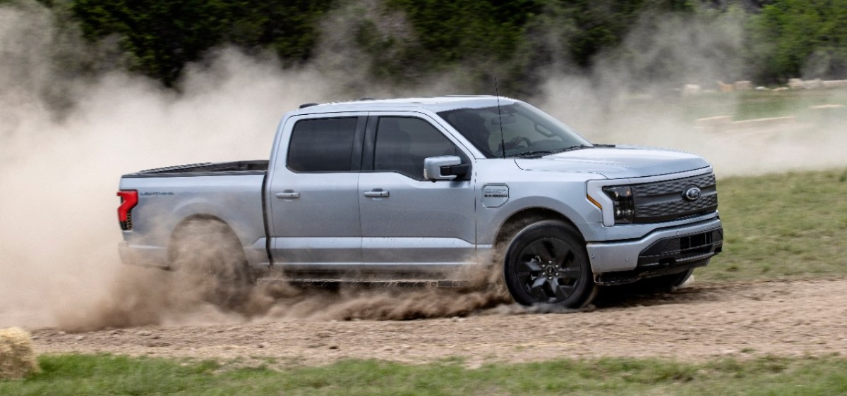 A grey F-150 Lightning driving in dirt