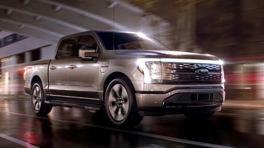 A gray 2022 Ford F-150 Lightning is driving on the road.