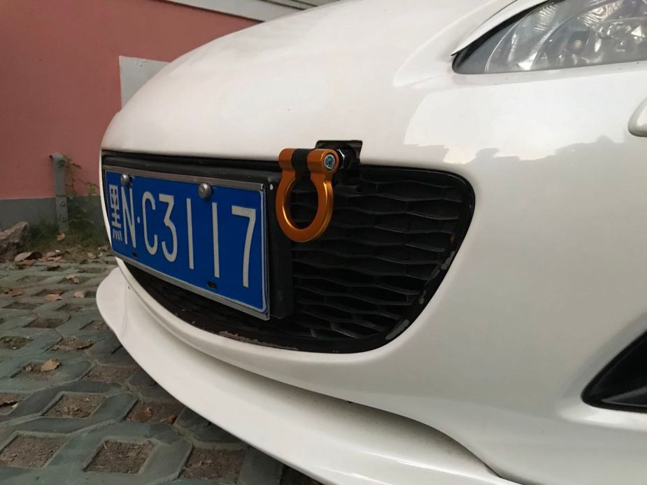 A loop-style tow hook screwed into the front bumper of a Mazda Miata sports car.
