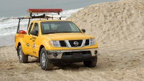 A yellow Nissan Frontier sits on a beach as a used truck.