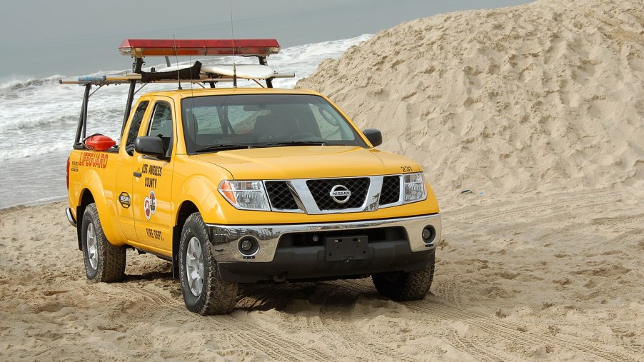 A yellow Nissan Frontier sits on a beach as a used truck.