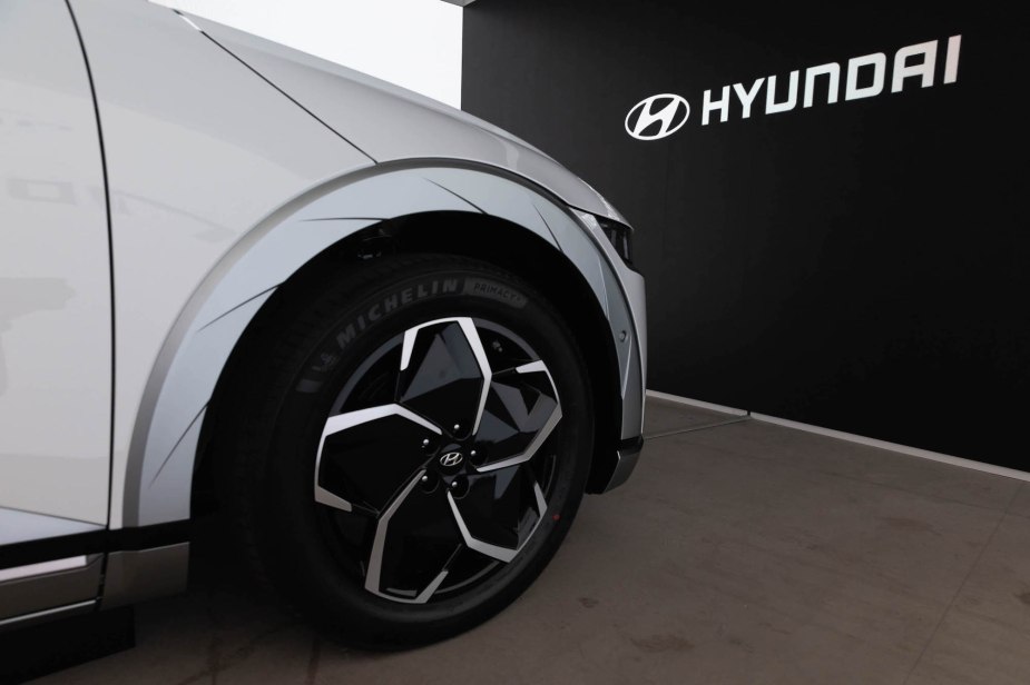 A silver Hyundai parked in front of a black background with Hyundai written on it. 