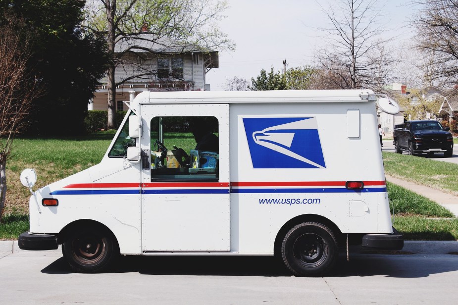 A Grumman LLV sits in a local neighborhood as a mail truck.