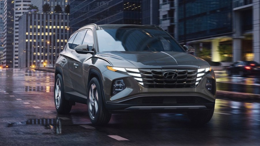 A gray 2022 Hyundai Tucson compact SUV is driving on a wet road.