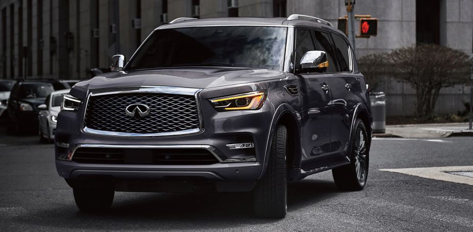 A grey 2022 Infiniti QX80 driving on the road. Is it worth $20,000 more than the Nissan Armada?