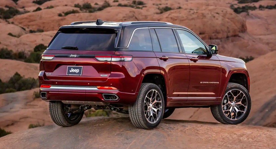 A red 2023 Jeep Grand Cherokee midsize SUV is on a rock. 