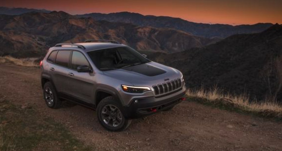 A gray 2021 Jeep Grand Cherokee midsize SUV is driving off-road. 