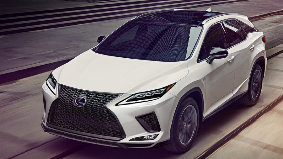 A white Lexus RX350 luxury midsize SUV is driving on the road.