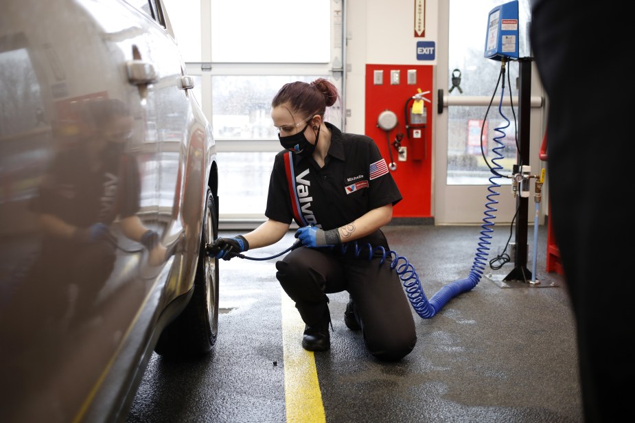 A Valvoline worker checks a car's tire pressure as part of regular maintenance