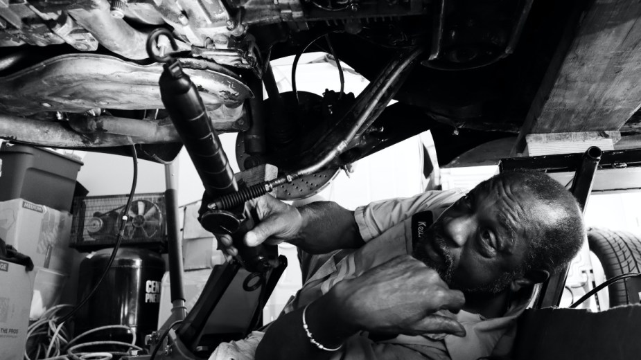 a man inspecting the undercarriage of a car, check for leaks to ensure your performs better